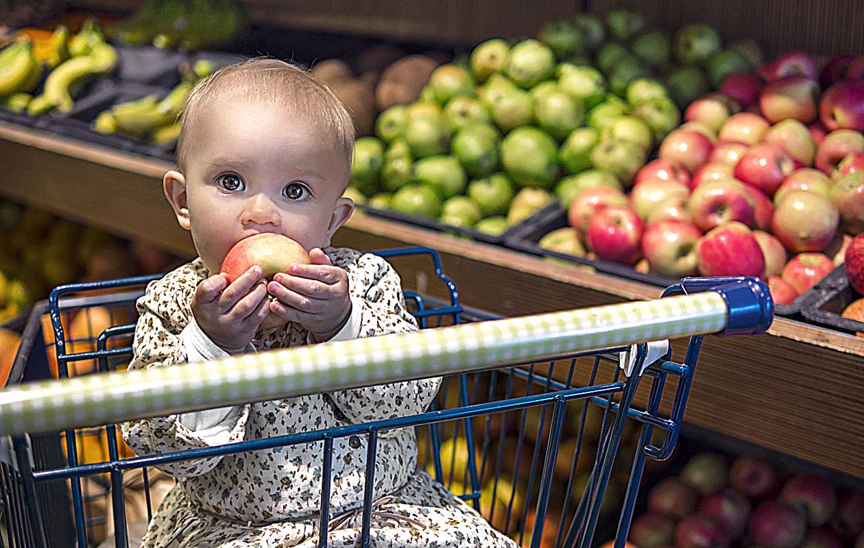 Lapsi kaupassa omena suussaan.
