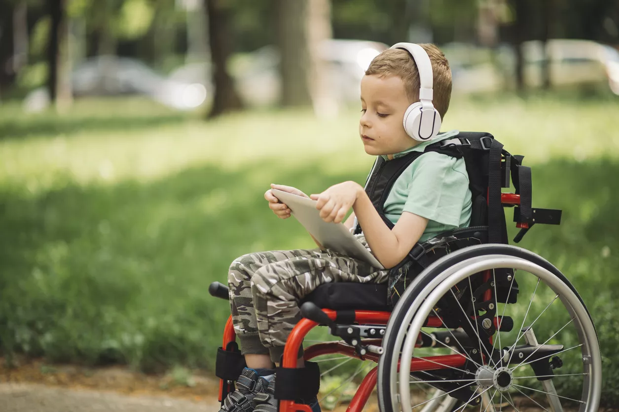 vammainen poika istuu pyörätuolissa ja kuuntelee musiikkia