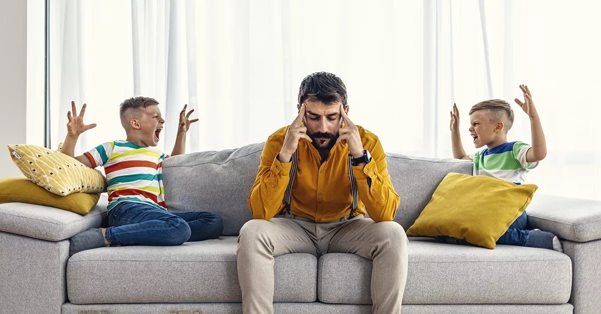 Lapselle huutaminen: mies ja lapset istuvat sohvalla