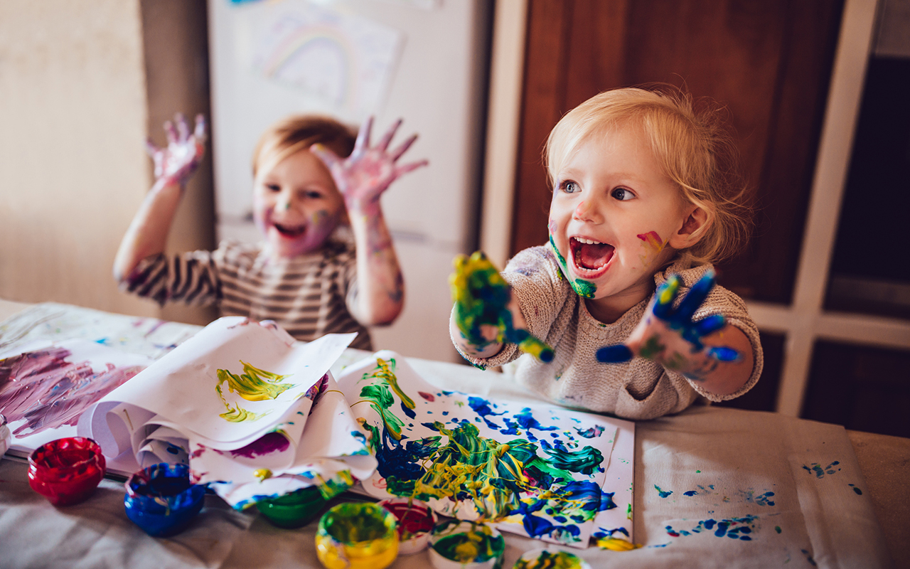 lapsilisä 2022 - Kaksi pientä lasta maalaa pöydän ääressä.