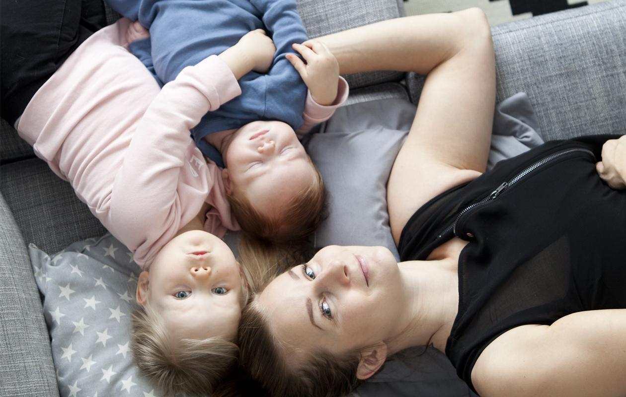 Bloggari Miia Metso sekä lapset Ruu ja Remu makoilevat sohvalla.