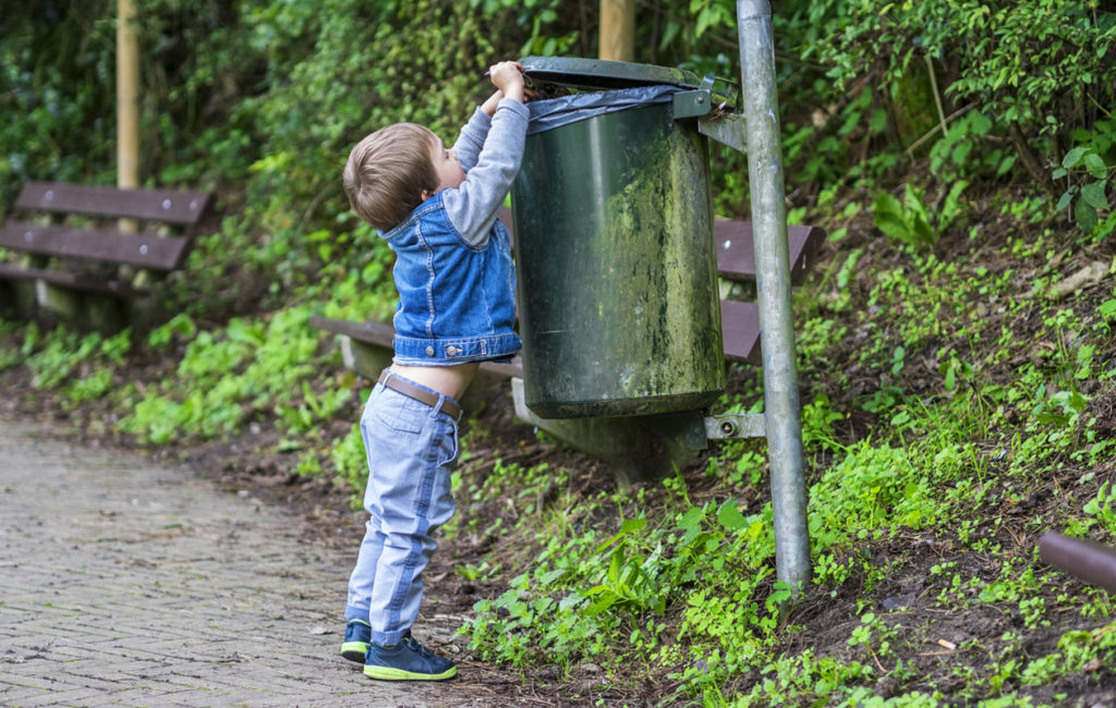 ympäristökasvatus: lapsi laittaa roskan roskakoriin