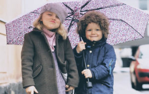 Lapset sateenvarjon alla kumppareissaan.