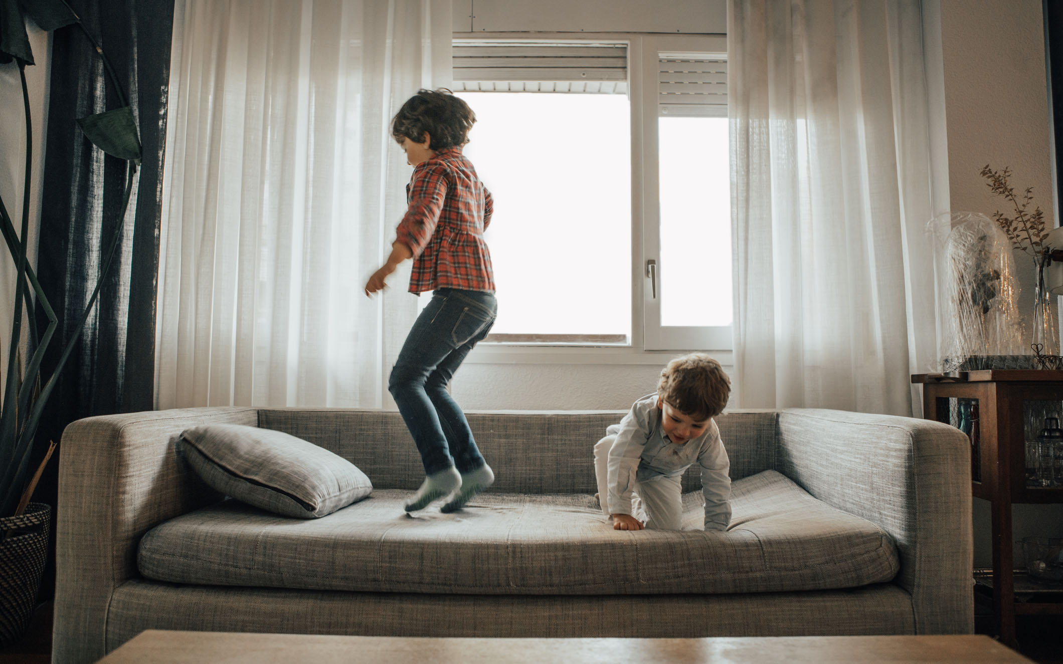 Брат и сестра спрыгнули. Брат и сестра прыгают на диване. Child jumping on the Sofa. Children on Sofa back view. Raising your spirited child book.