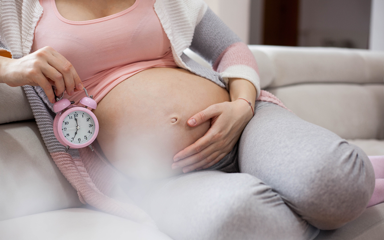 Raskaana oleva nainen loikoilee kello kädessä sohvalla. Kun raskaus on täysiaikainen ja lapsivettä tulee kohdusta, synnytys alkaa olla käsillä. Toisinaan synnytys joudutaan käynnistämään sen jälkeen, kun lapsivedenmeno on tapahtunut.