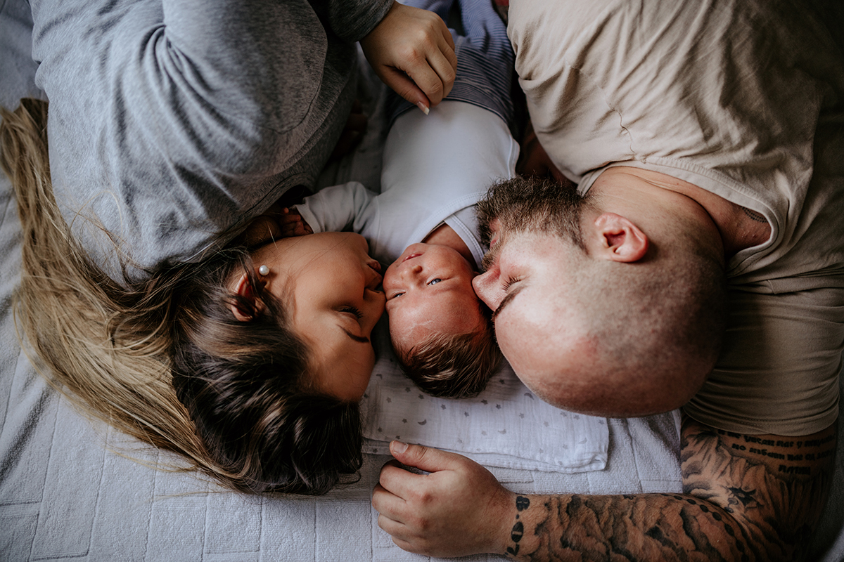 Mies, nainen ja vauva makaavat sängyssä