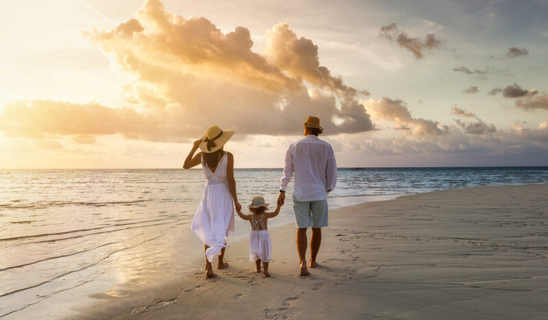 Uusyksinäisyys: Perhe kävelee rannalla auringonlaskussa