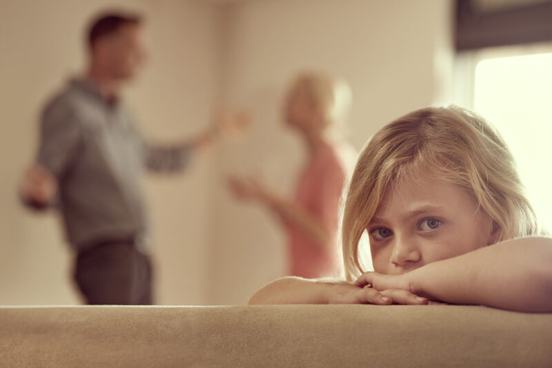 luottamuus parisuhteessa: surullinen lapsi, taustalla kinastelevat vanhemmat