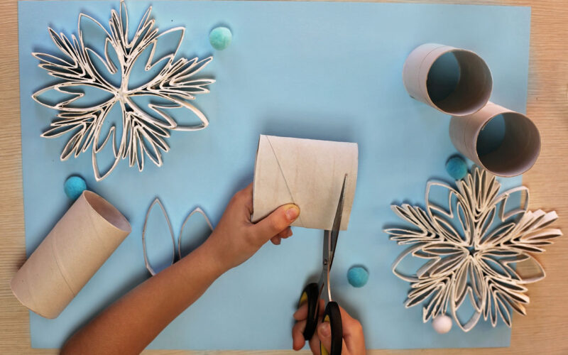 jouluaskartelu: lapsi leikkaa vessapaperihylsyistä tähtiä