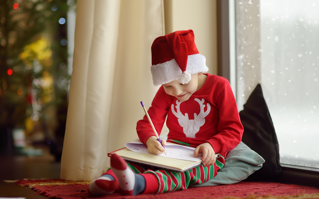 joulun toivotukset: lapsi piirtää ja kirjoittaa kirjettä.